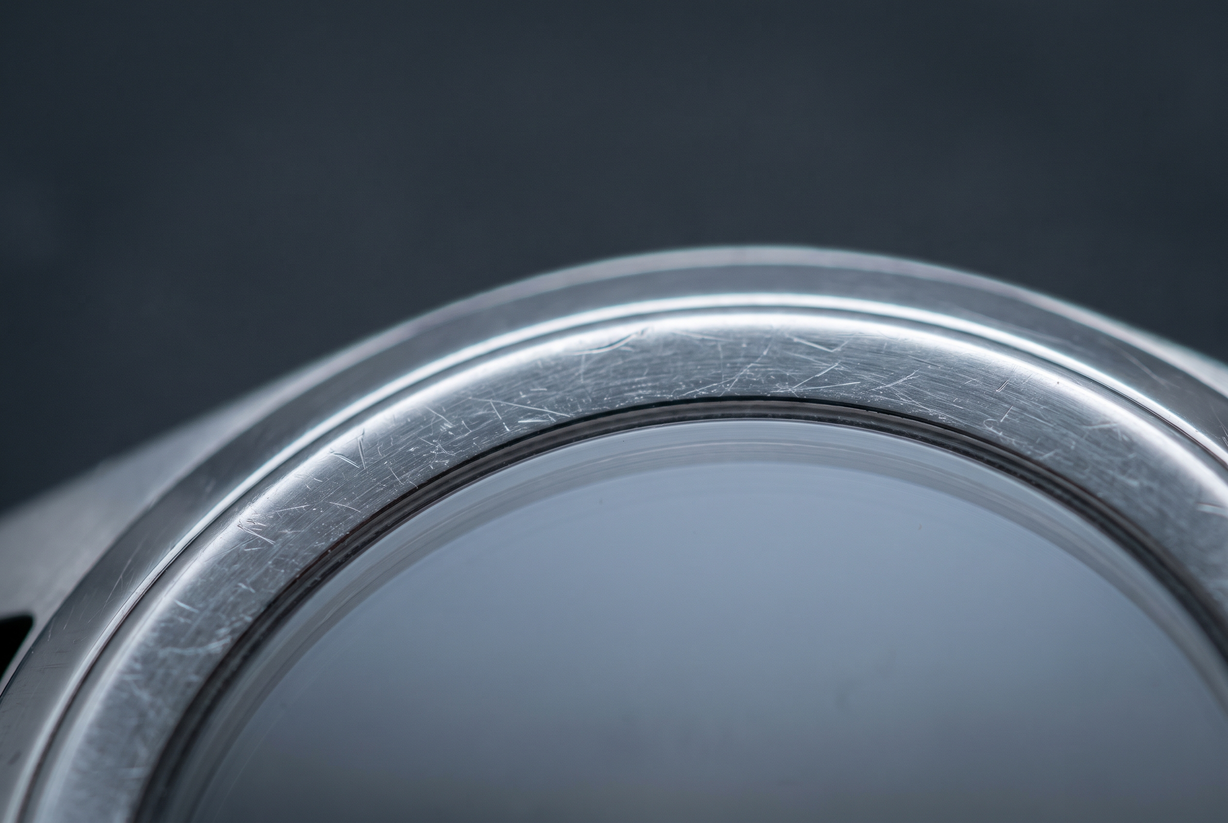 Macro de la tranche polie d'un boîtier en acier révélant de fines micro-rayures sous la lumière