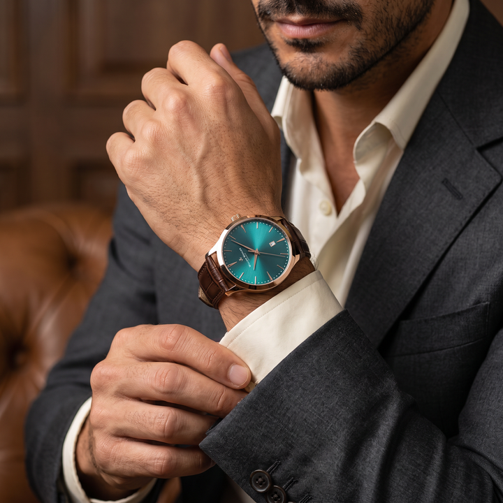 Montre homme Ambre Turquoise William Wohler portée au poignet — boîtier or rose 41 mm, cadran turquoise et bracelet cuir alligator marron